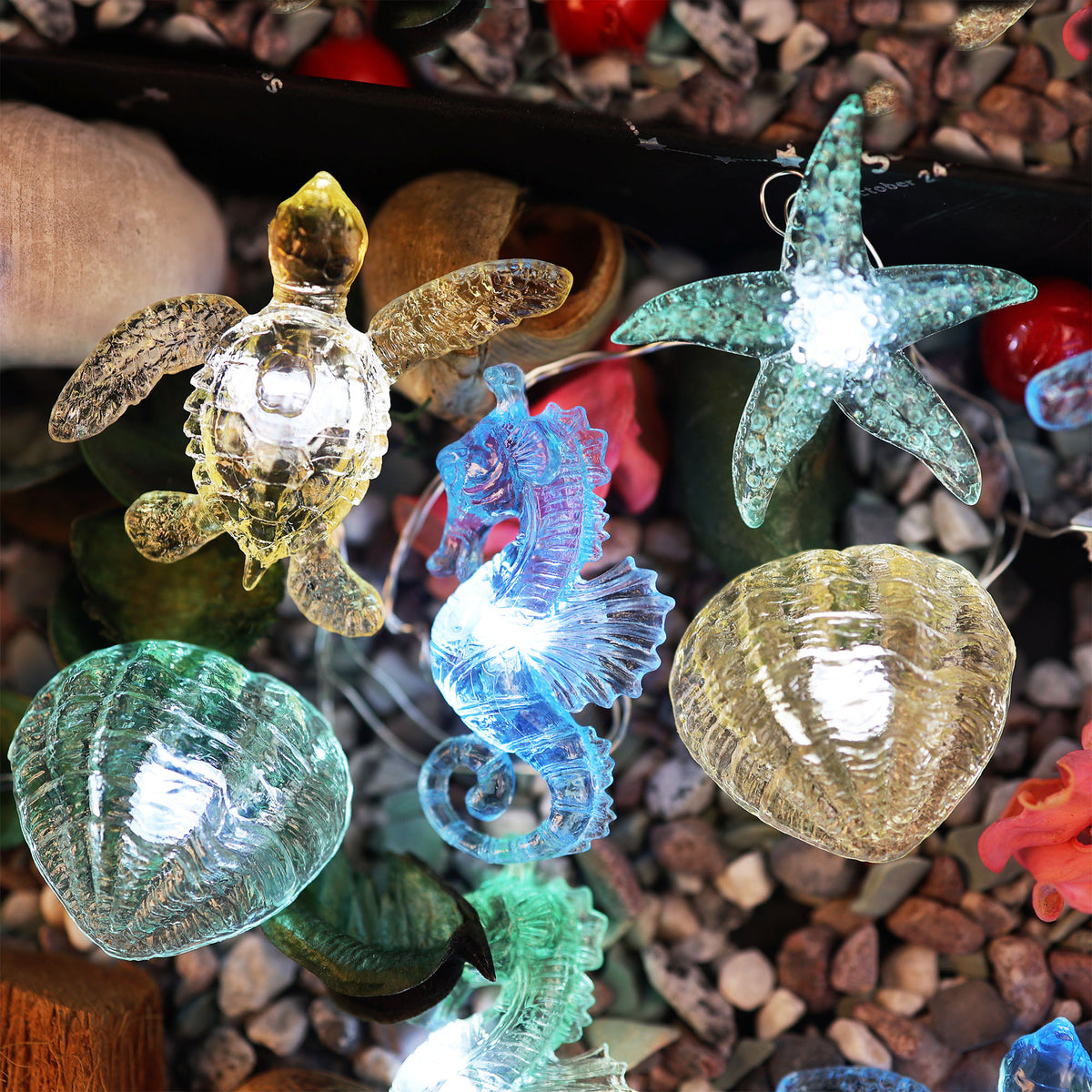 Close-up of translucent sea turtle, seahorse, starfish and shell fairy lights on a pebble display
